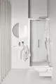 Weißes Wand-WC von Ideal Standard, im modernen Badezimmer mit Dusche, Handtuch und runder Wandspiegel, vor hellgrauer Wand und Boden.